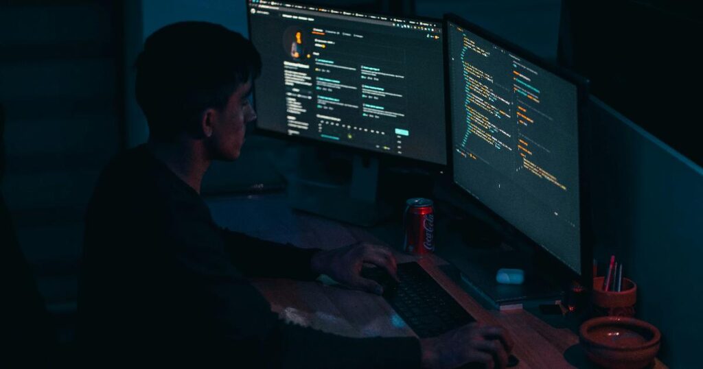 Сцена в офисе с разработчиком, который проверяет сгенерированный код; код подешевел, но разработка по-прежнему требует ревью и решений